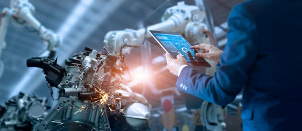 A person holding a tablet and looking at a robot