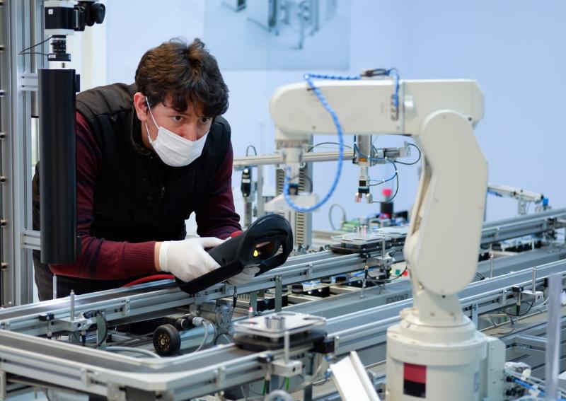 Man looking closely to a robotic arm